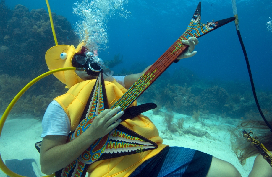 In this photo provided by the Florida Keys News Bureau, Jeff Wright, costumed as a seahorse, rocks with a fake guitar, Saturday, July 11, 2015, during the Underwater Music Festival in the Florida Keys National Marine Sanctuary off Big Pine Key, Fla. The annual event attracted hundreds of divers and snorkelers who listened to a local radio station's four-hour broadcast piped beneath the sea via underwater speakers, featuring music programmed for the subsea listening experience as well as coral reef conservation messages. (Bob Care/Florida Keys News Bureau via AP)