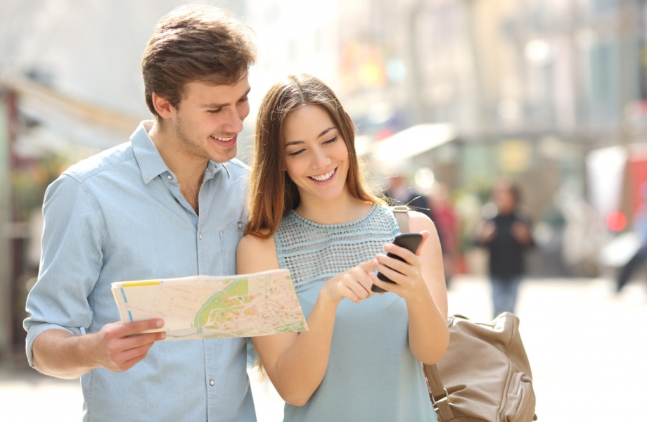 Couple of tourists consulting a city guide and smartphone gps in the street searching locations