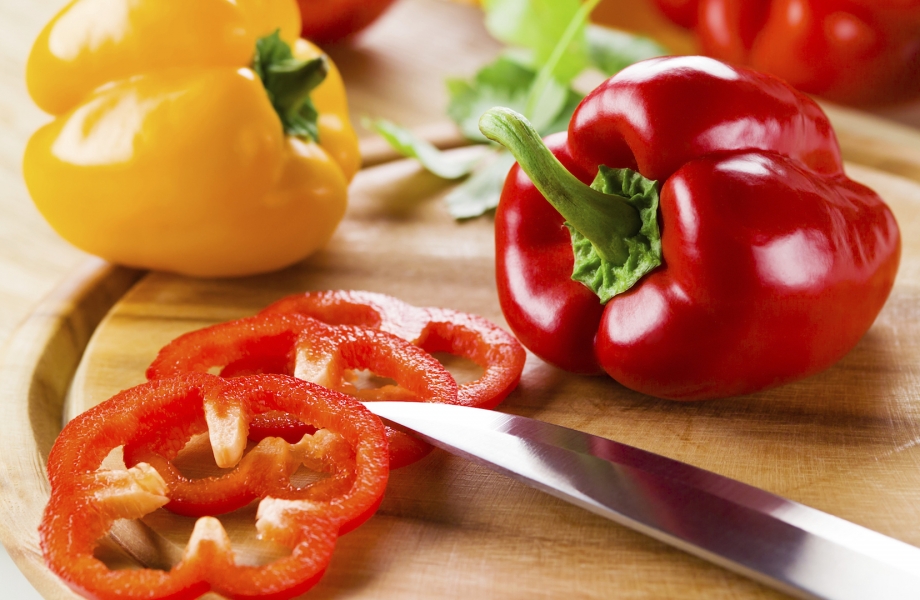 Organic paprika peppers with slice over wooden table