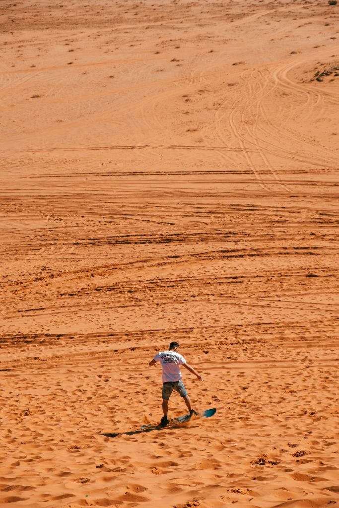 Man sandboarding down a dune.