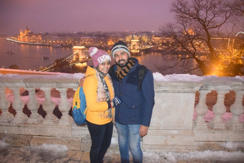 A couple posing with Budapest lit with lights as a background
