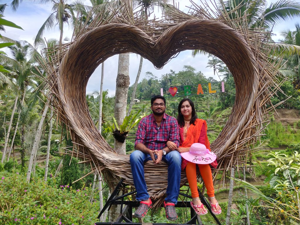 A couple posing with I love Bali sign as the background on their first international trip