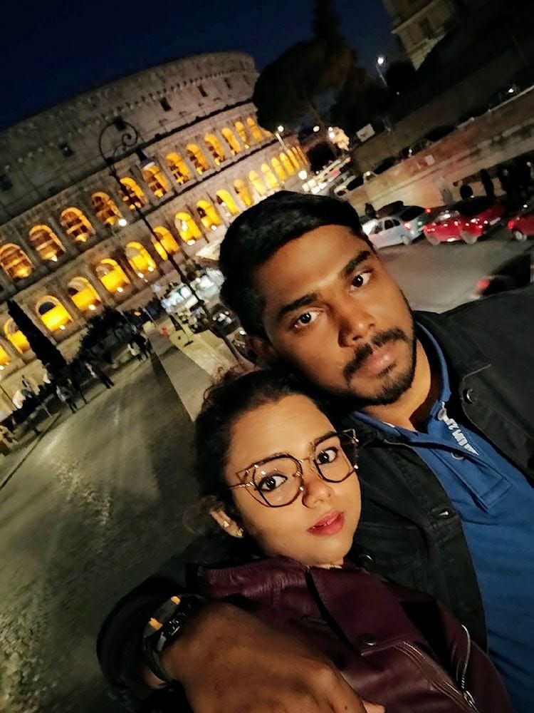 A picture of a couple taken in front of the colosseum in Rome