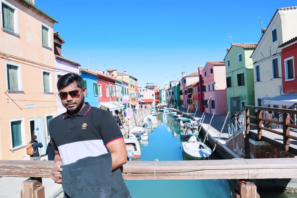 A picture of guy standing in the island of Burano in Italy