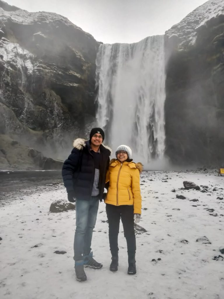 A couple picture with waterfalls as the background on their honeymoon to Iceland